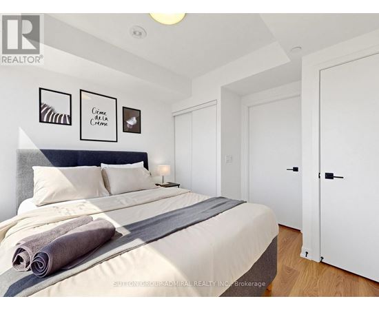 A bedroom with a large bed and a city view through the window.