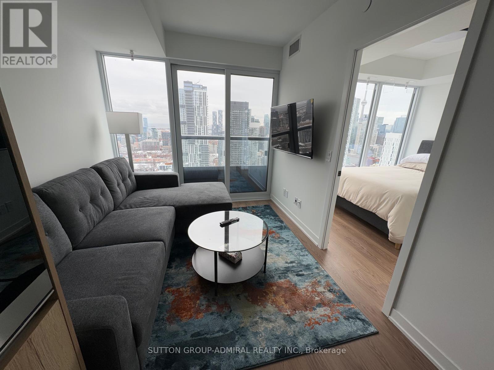 A living room with a grey couch and a round table in the middle.