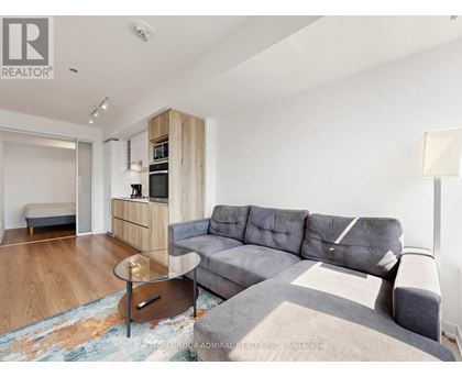 A living room with a grey couch and a round table in the middle.