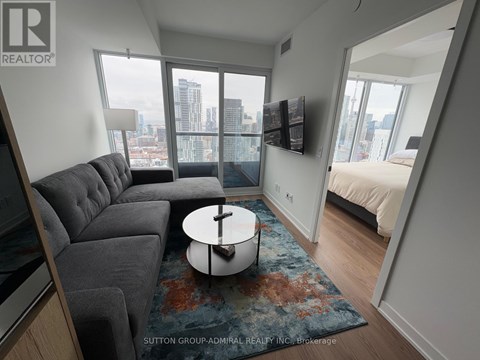 A living room with a grey couch and a round table in the middle.