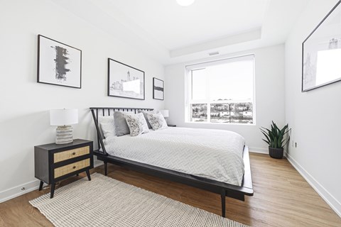 A bedroom with a bed, nightstand, and pictures on the wall.