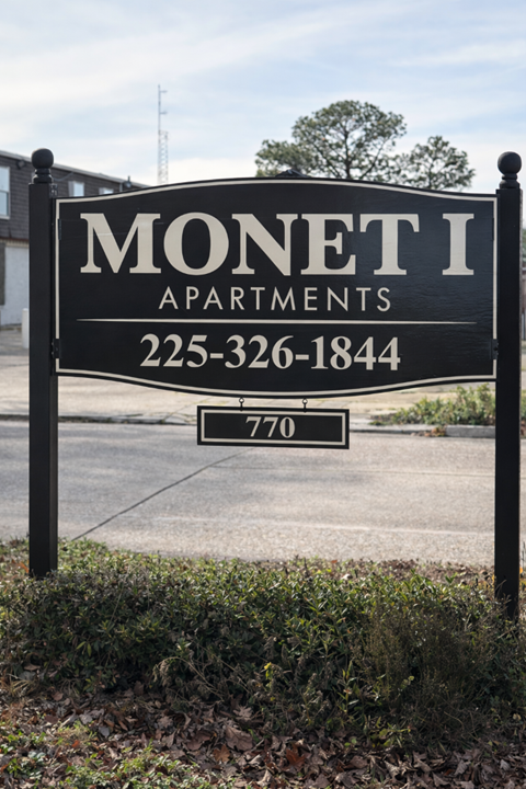 A black and white sign for Monet I Apartments with a phone number and a smaller sign below it.