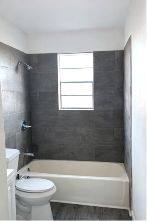 A bathroom with a toilet, tub, and window.
