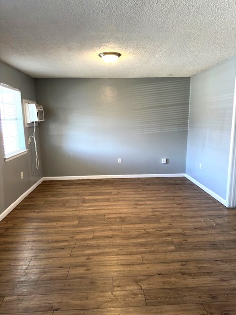 A room with wooden flooring and a window with blinds.