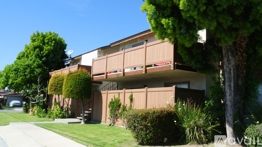 A house with a brown facade and green trees in front.