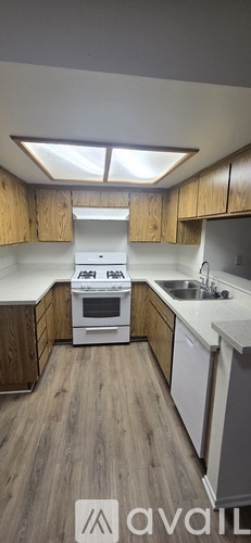 A kitchen with wooden cabinets and a white stove top oven.