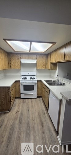 A kitchen with wooden cabinets and a white stove top oven.