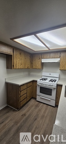 A kitchen with wooden cabinets and a white stove top oven.