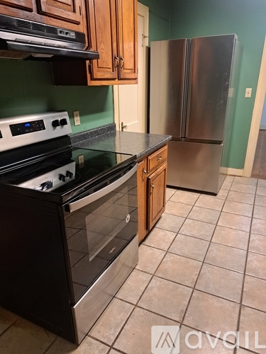 A kitchen with a black stove top oven and a stainless steel refrigerator.