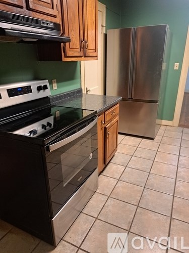 A kitchen with a black stove top oven and a stainless steel refrigerator.