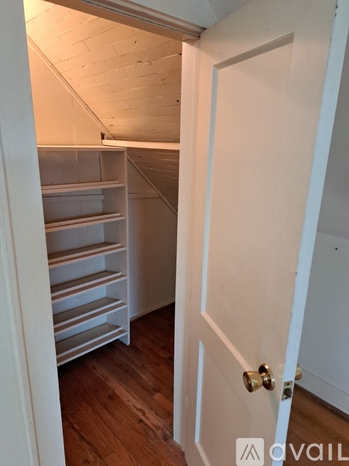 A white door is open to a room with a white ceiling and wooden floors.