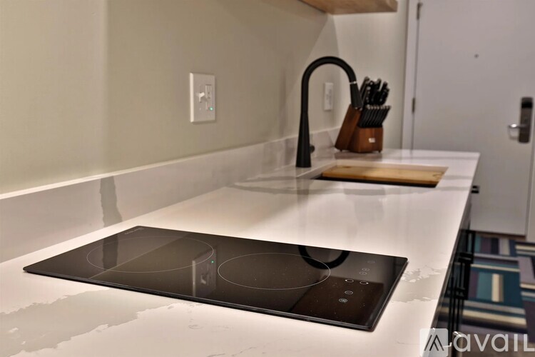 A kitchen counter with a stove top and a knife block.