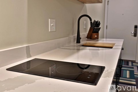 A kitchen counter with a stove top and a knife block.