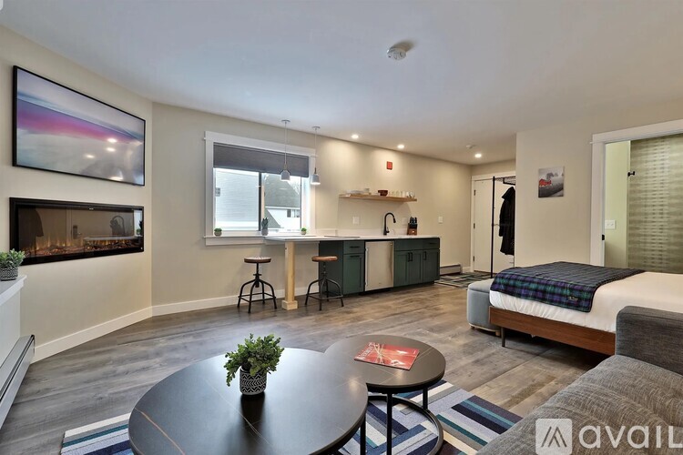 A living room with a fireplace and a bed in the background.