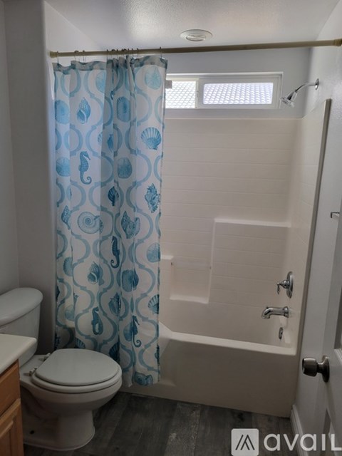 A bathroom with a toilet, a shower with a blue curtain, and a white door.