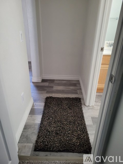 A hallway with a rug on the floor and a door on the right.