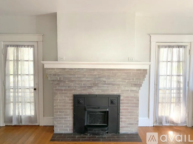 A fireplace with a black grate in a room with white walls.