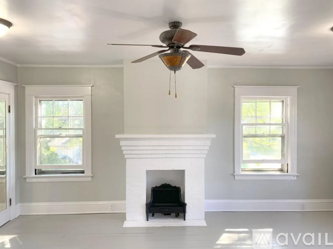A living room with a fireplace and a ceiling fan.