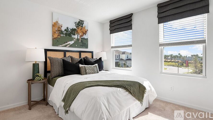 A bedroom with a large bed and a painting of a tree-lined path.