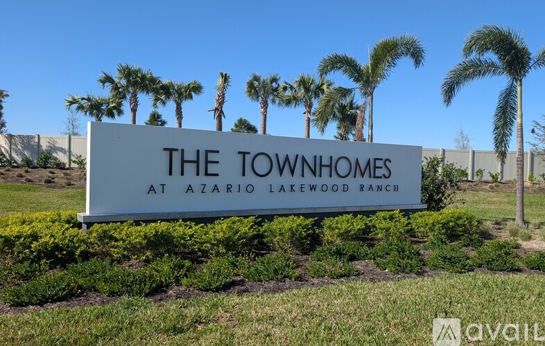A sign that says "The Townhomes at Azario Lakewood Ranch" in front of some palm trees.