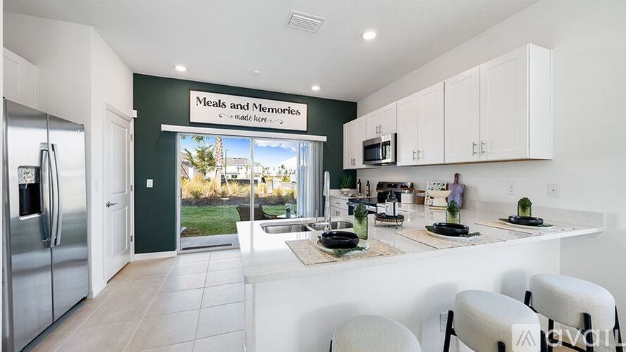 A kitchen with a fridge, sink, and a window with a view of a house.