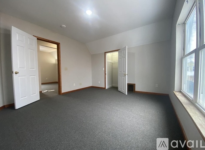 A room with a carpeted floor and a window on the right side.