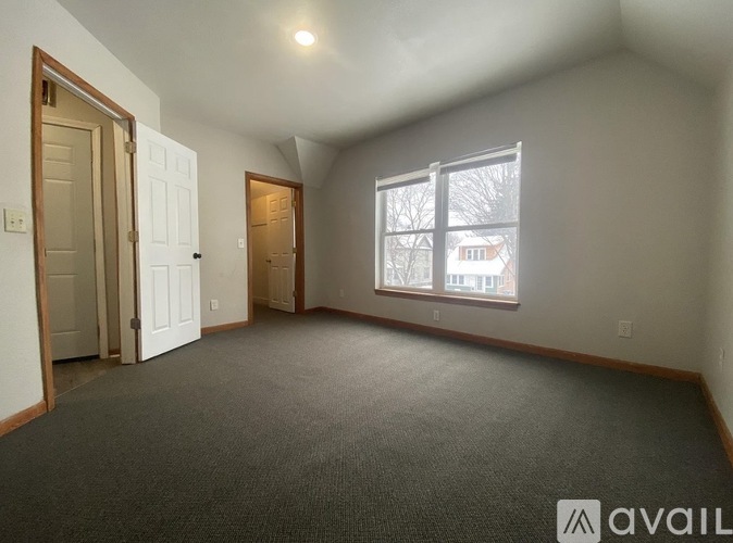 A room with a carpeted floor and a window showing a view of a building outside.