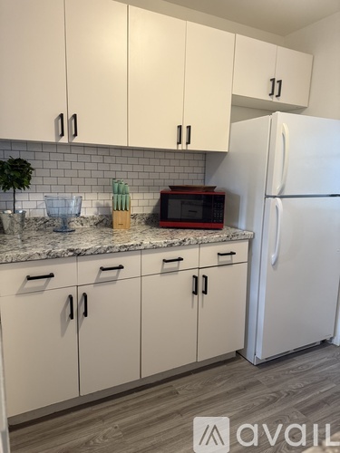 A kitchen with white cabinets and a white refrigerator.