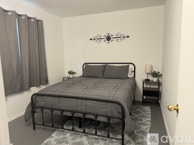 A bedroom with a black metal bed frame and grey bedding.