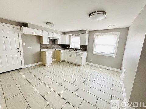 A kitchen with a tile floor and white appliances.