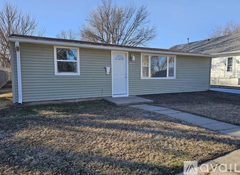 A small house with a white door and two windows is for sale.