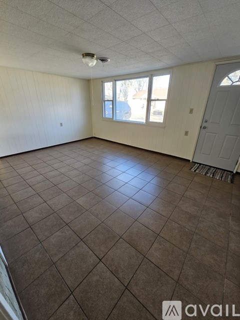A room with brown tiled flooring and white walls.