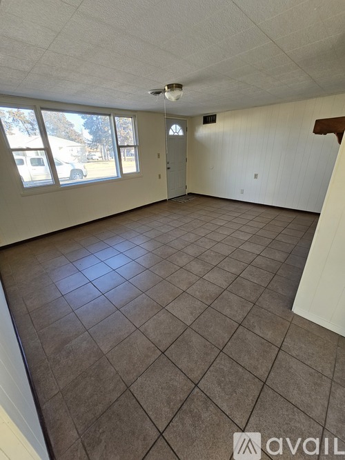 Empty room with tile flooring and large windows.