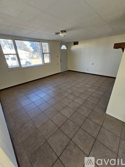 Empty room with tile flooring and large windows.