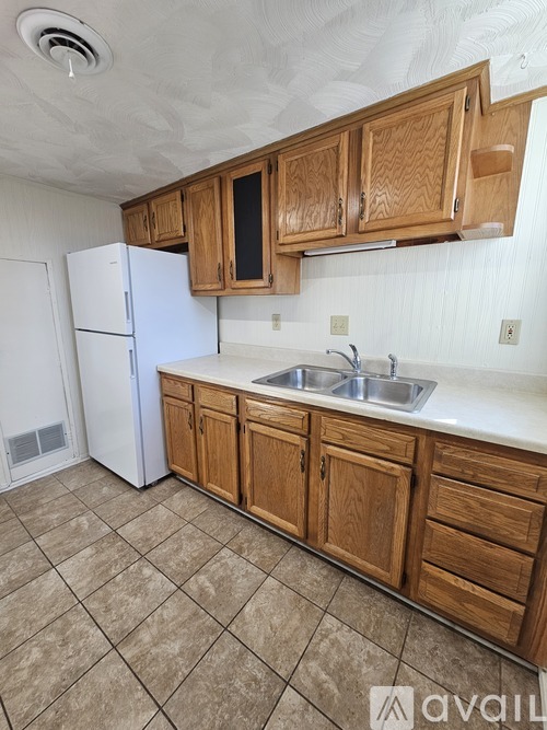A kitchen with wooden cabinets and a white refrigerator.