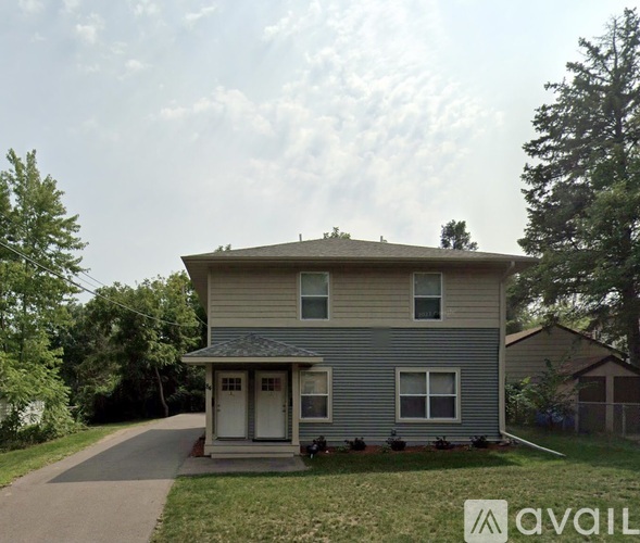 A house with a grey siding and a white door is available for rent.