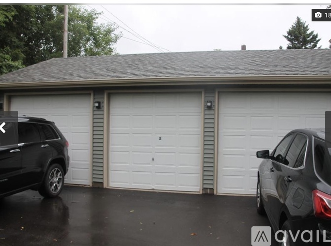 Two cars are parked in front of a two-car garage.
