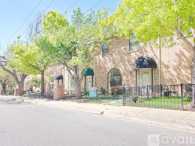 A brick house with a green awning is on the corner of a street.