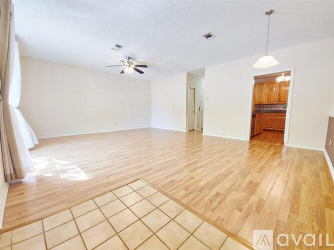 A spacious room with wooden flooring and a ceiling fan.