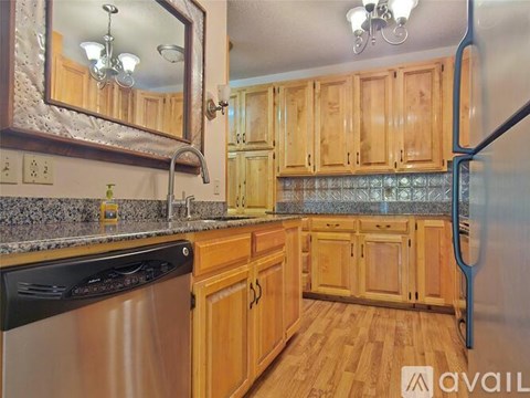 A kitchen with wooden cabinets and a stainless steel dishwasher.