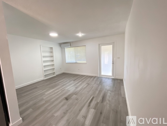 A spacious room with wooden flooring and white walls.