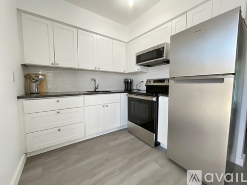 A kitchen with white cabinets and a stainless steel refrigerator.
