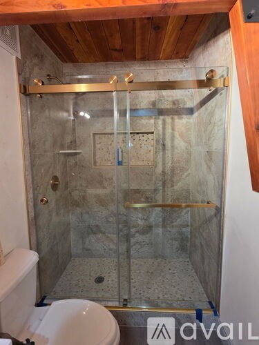 A bathroom with a glass shower stall and a toilet.