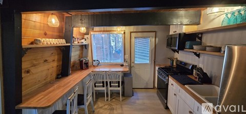 A kitchen with a wooden bar and stainless steel appliances.