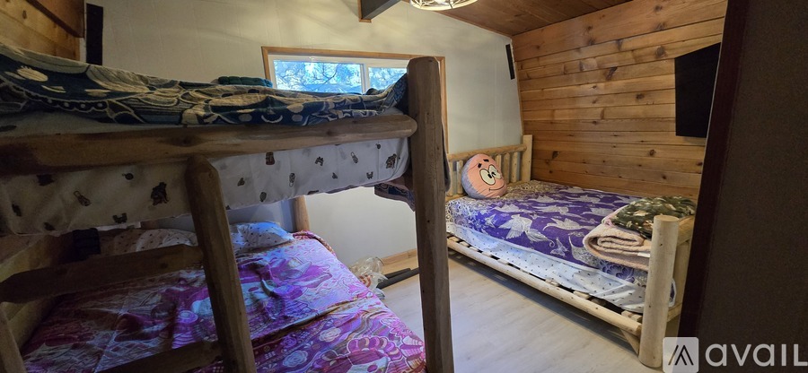 A wooden bunk bed with a single bed in a room with wooden walls.