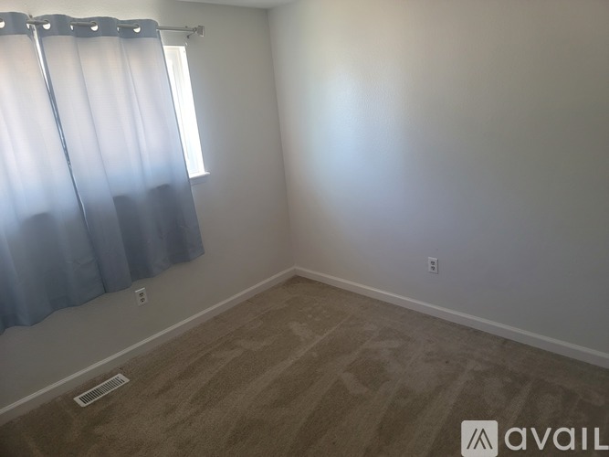 A room with a window covered by blue curtains and a carpet on the floor.