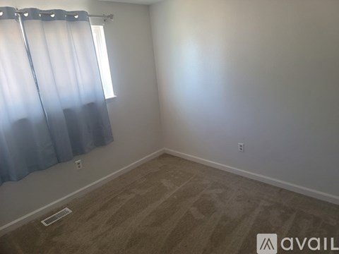 A room with a window covered by blue curtains and a carpet on the floor.