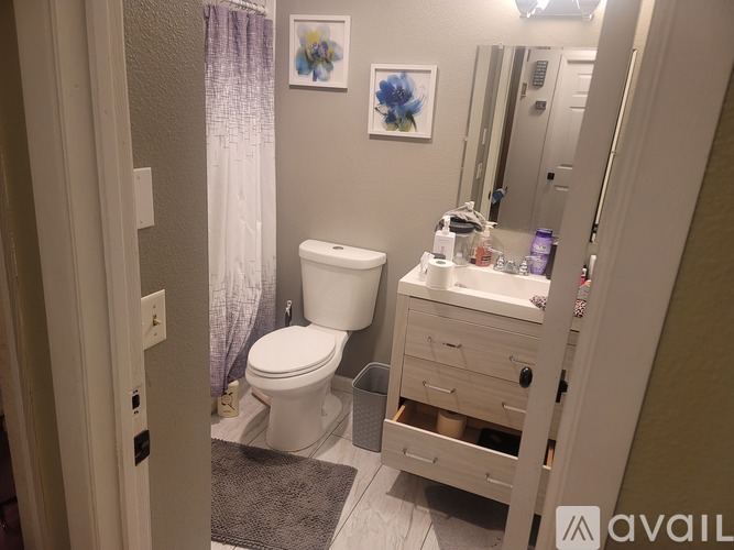 A bathroom with a toilet, sink, and mirror.