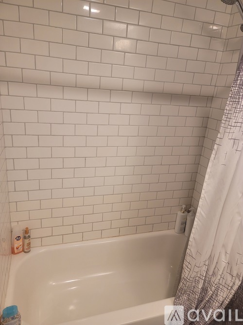 A white tiled bathroom with a white tub and a white shower curtain.