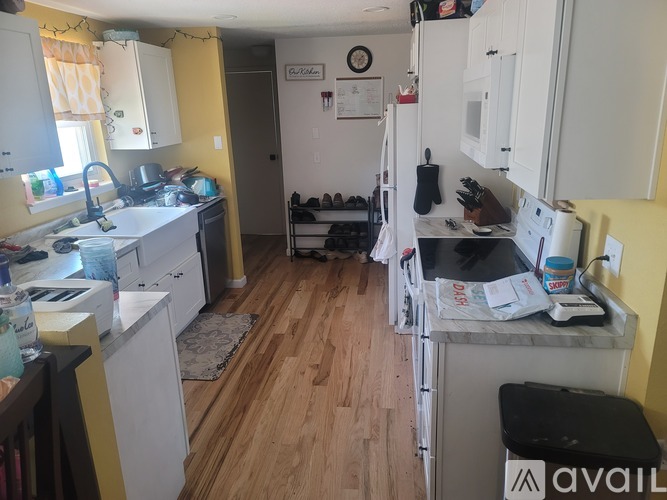 A kitchen with white cabinets and a wooden floor.